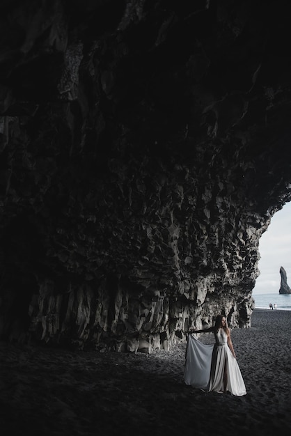 Destination iceland wedding. a wedding couple is walking along\
the black beach of vic.