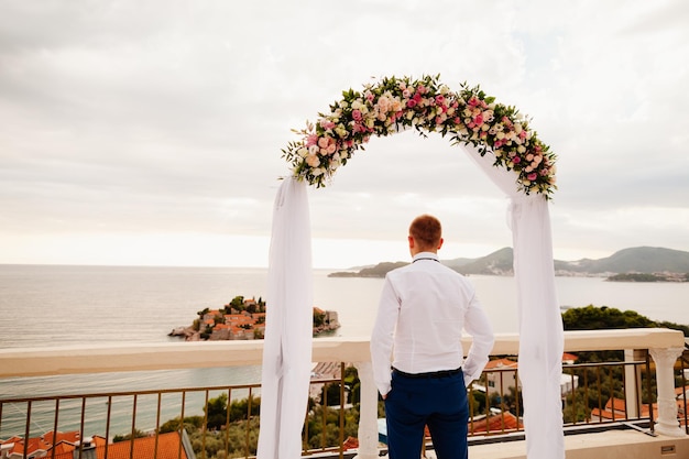 Destination wedding groom at sunset with sea view Back view