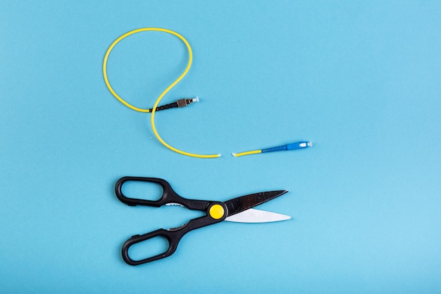 Destroy optical SC fiber by scissors. Isolated on blue.