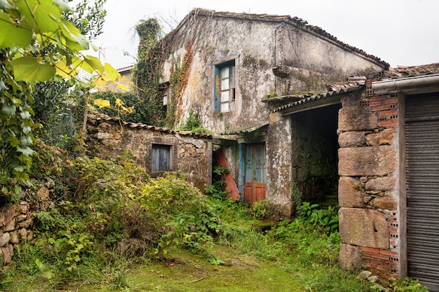 Фото Разрушенный заброшенный дом в испании, европе. разбитые окна, поврежденные стены и заросший сад.