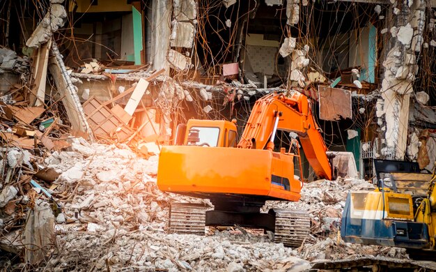 Photo destroyed building industrial building demolition by explosion abandoned concrete building with rubble and scrap earthquake ruin damaged or collapsed building from hurricane disaster backhoe