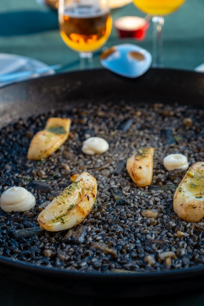 Detail of the black rice with cuttlefish and young garlic with aioli a plate of dry rice