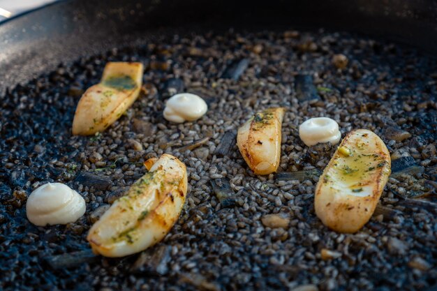 Detail of the black rice with cuttlefish and young garlic with aioli a plate of dry rice