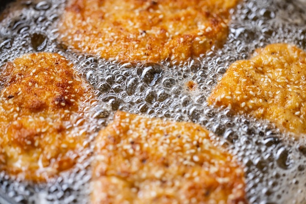 Foto dettaglio delle bolle nell'olio di frittura mentre gli schnitzel si friggono nella padella