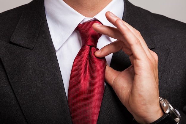 Photo detail of a businessman adjusting his necktie