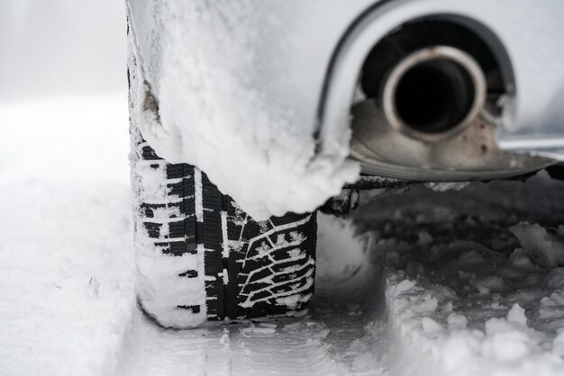 冬の雪の上の車のタイヤと排気のディテール。