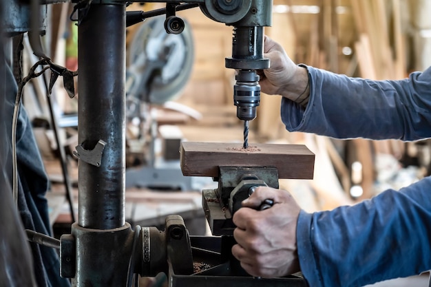 Foto particolare di un carpentiere che fora un legno con un trapano