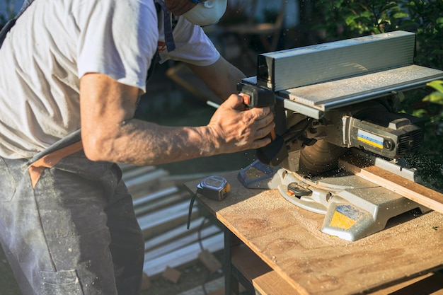 Detail of carpenter39s arms cutting wood with circular saw