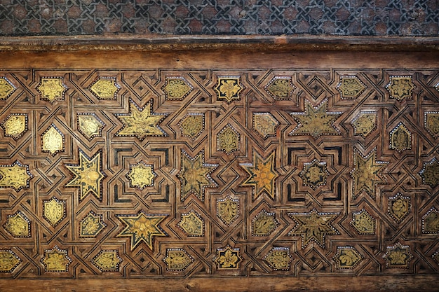 Foto dettaglio di una porta in legno intagliato nell'alhambra di granada, spagna. porta araba scolpita in stile islamico.