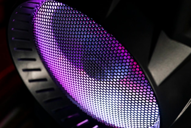 Detail of the case of a gaming pc with fan illuminated by rgb led and protection net