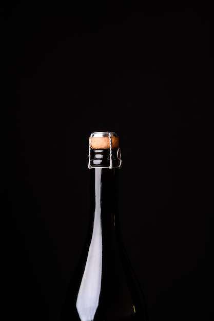 Detail of champagne bottle with a cork on a black background