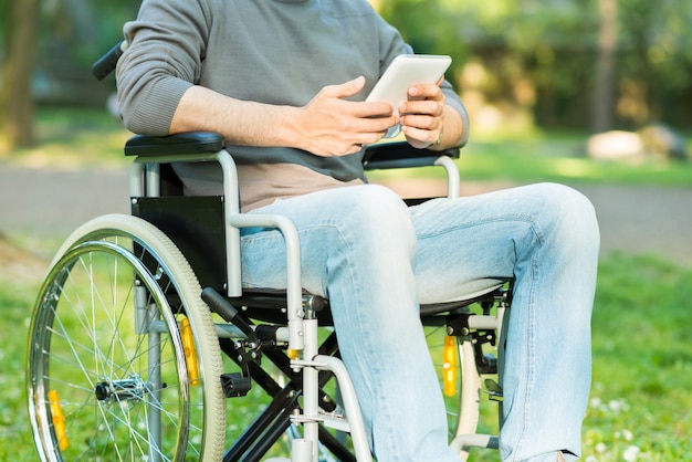 Detail of a disabled man using a tablet in a park