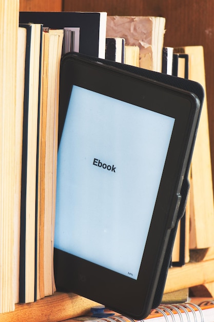 Particolare di un lettore di ebook tra i libri classici