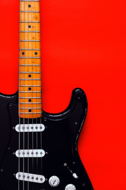 Photo detail of electric guitar on a red surface