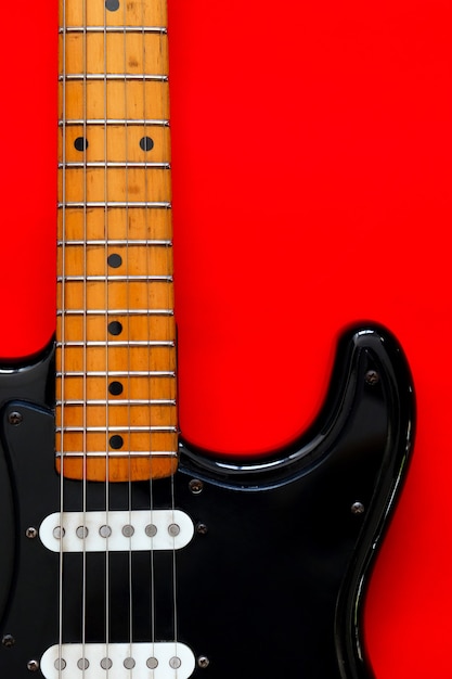 Photo detail of electric guitar on a red surface