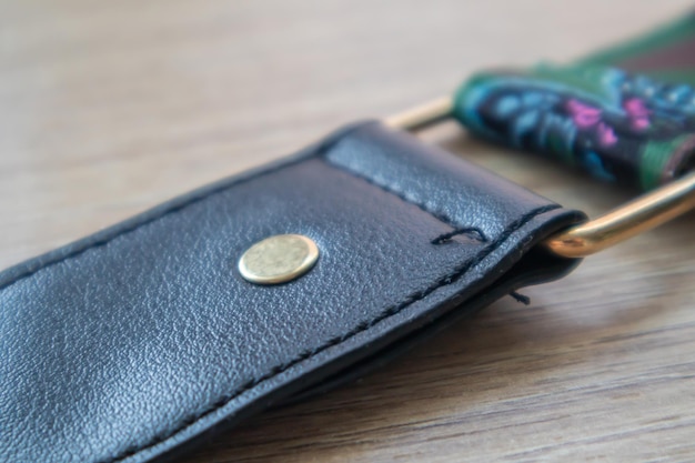 Detail of a fashionable black leather handbag close-up. Fashion concept. Details of a belt, metal buckle, fastener, sewing threads, macro photography. Stylish female accessory.