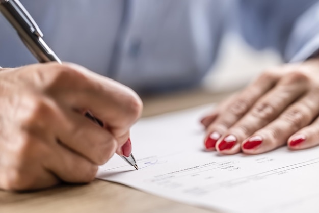 紙の契約またはペンとの契約に署名する女性の手の詳細