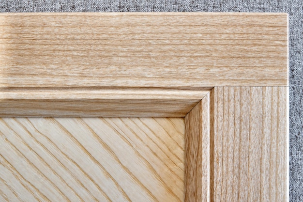 Detail of furniture facade made of light veneer and solid ash wood on gray textile background