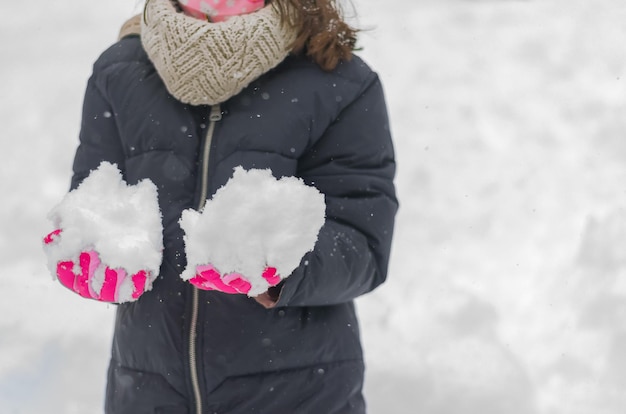 Detail of the gloves with snow and of the mask for coronavirus of an unrecognizable girl.