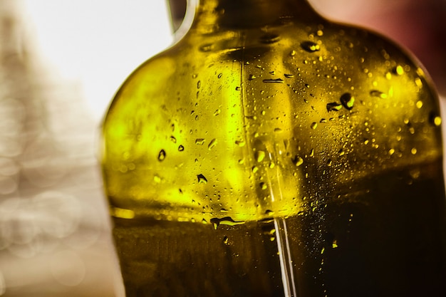 Foto particolare di una bottiglia di vetro verde contenente olio d'oliva utilizzato in cucina