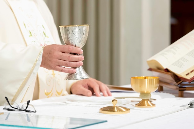 Particolare della mano di un sacerdote che regge la coppa con il vino sacro