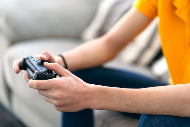 Photo detail of the hand with the joystick of a young guy playing a game on the console in his living room