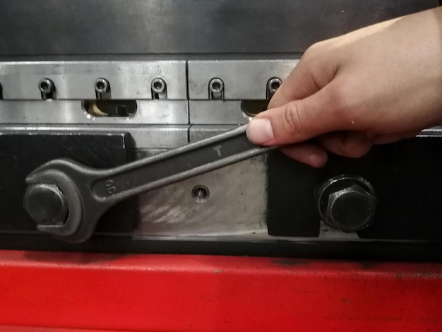 Detail of a hand with a spanner loosening the screw of a machine