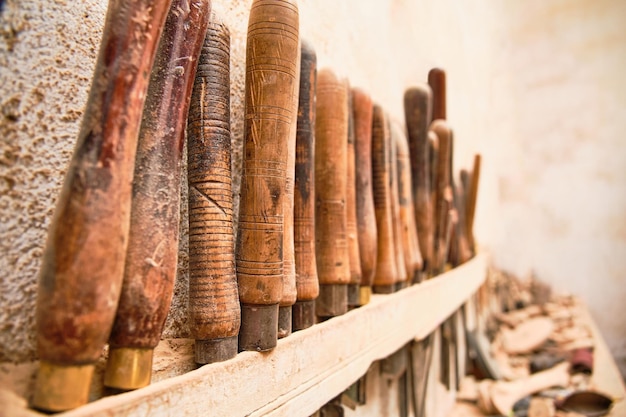 Foto particolare dei manici di attrezzi per intagliare il legno di un laboratorio di falegnameria artigianale appesi al muro