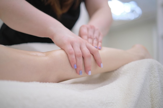 Photo detail of hands massaging human calf muscletherapist applying pressure on female leg