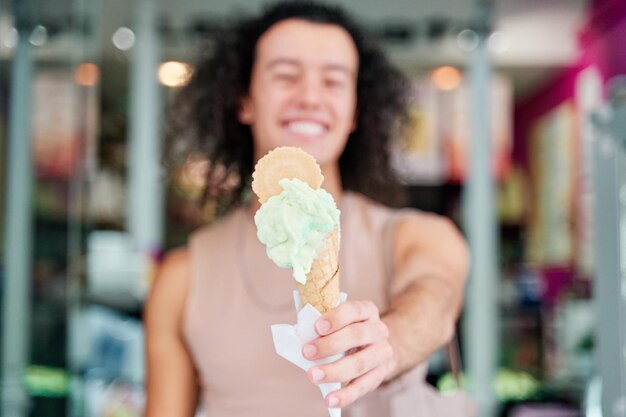 detail of an ice cream cone held by a mans hand outoffocus man in the background