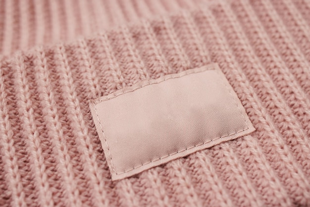 Detail of a knitted pink hat with an empty round leather tag mockup closeup