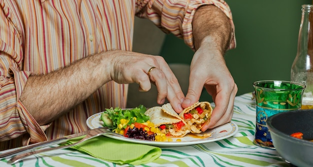 Detail of man hands eating mexican fajitas and salad