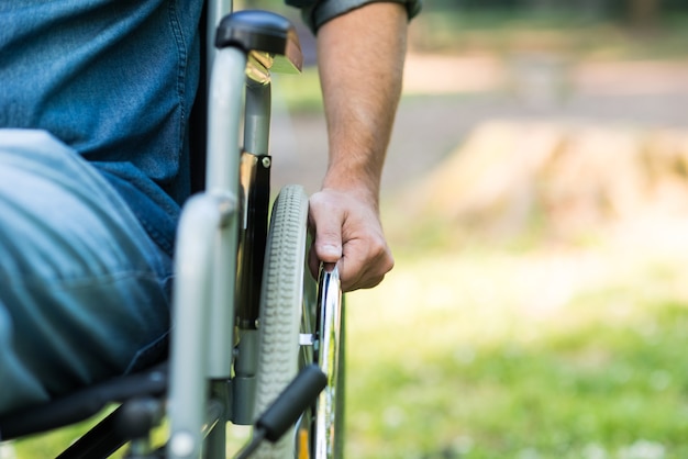 Dettaglio di un uomo che utilizza una sedia a rotelle in un parco. copia-spazio sul lato destro