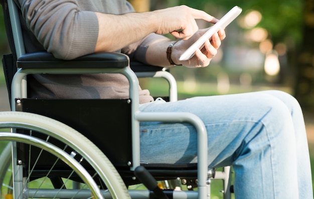 Detail of a man using a wheelchair in a park