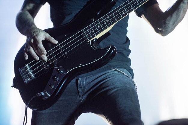 Detail of a musician playing on a bass guitar at concert