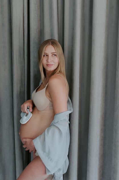 Detail of a pregnant woman dressed in white clothes, with both hands holding the belly