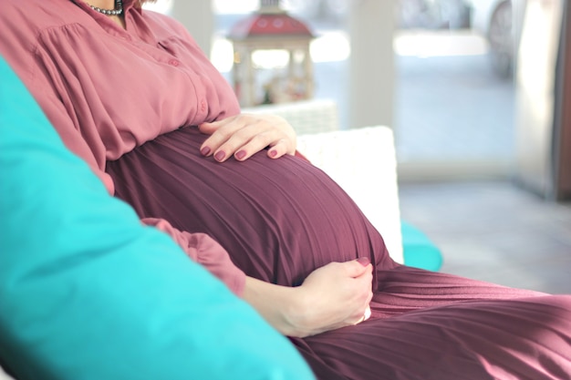 Detail of pregnant woman with red dress with hands on belly