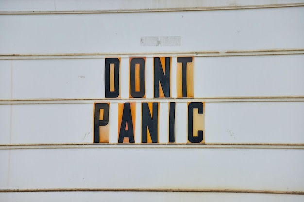 Photo detail of road sign all white with black capital letters dont panic from hitchhikers guide to the ga