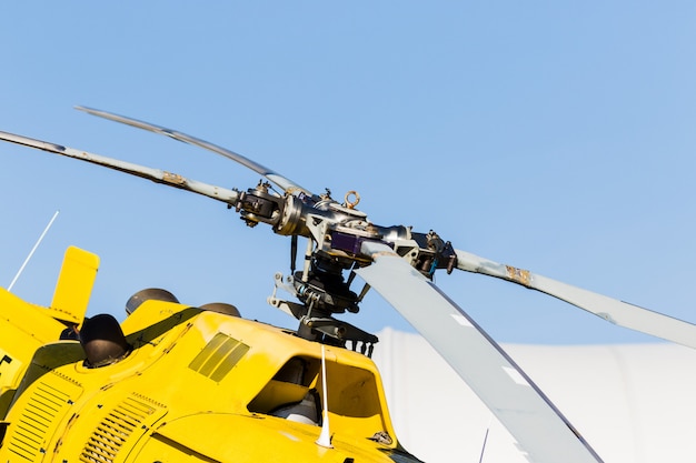 Detail of the rotor of a yellow helicopter with the sky in the background