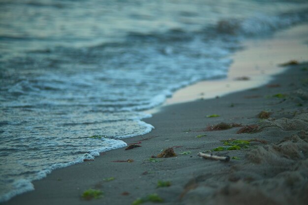 Detail of sea water shattering shore on sand beach.