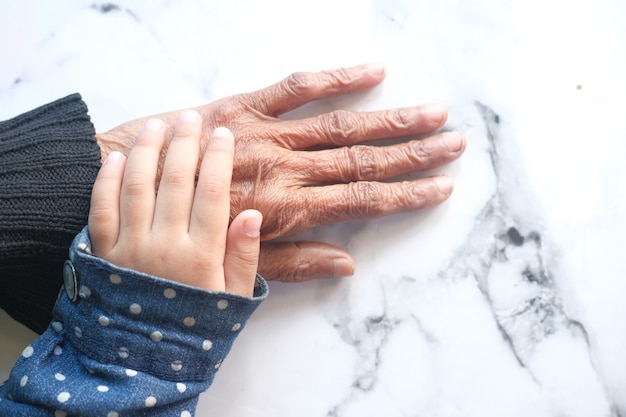 Foto colpo di dettaglio della ragazza del bambino che tiene la mano di una donna anziana