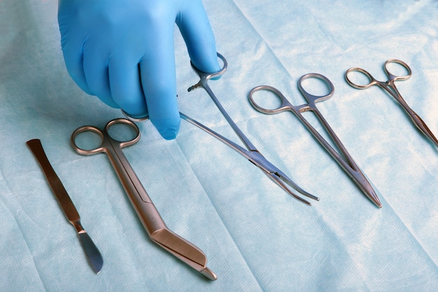 Detail shot of sterilized surgery instruments with a hand grabbing a tool