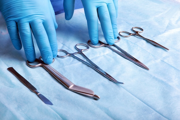 Detail shot of sterilized surgery instruments with a hand grabbing a tool 