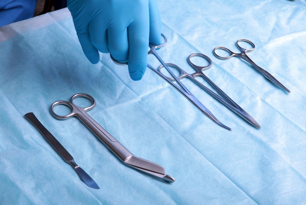 Detail shot of sterilized surgery instruments with a hand grabbing a tool 