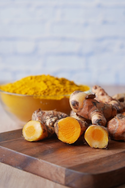 Photo detail shot of turmeric root in bowl on table