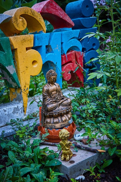 Detail of small Buddha statue and colorful letters in garden