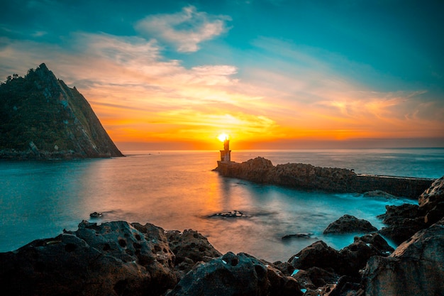 Detail of the sun behind the lighthouse at sunset in the town of Pasajes San Juan