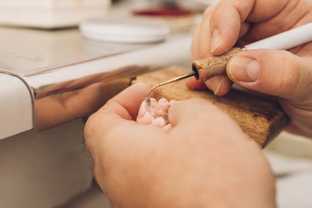 Photo detail of the tip of a sharpener with which a professional applies wax to a dental mould in a dental laboratory specialising in dental bone ceramics.