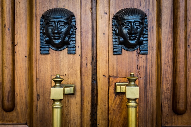 Detail of two bronze Sphinx heads on an old wooden door - around 100 years old, Italian palace in North Italy