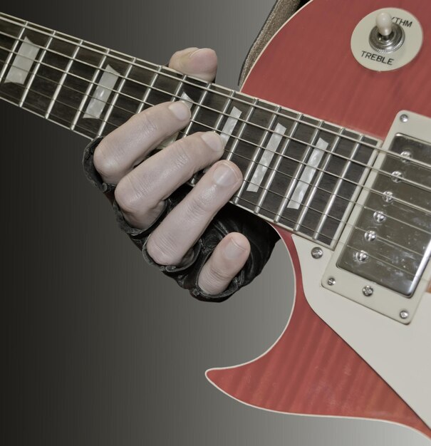 Detail van de hand van de man die een elektrische gitaar speelt